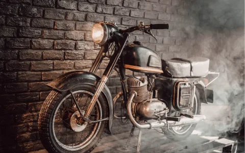 Vintage motorcycle displayed indoors against a brick wall with atmospheric smoke, example of a collectable asset under SMSF rules