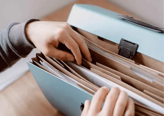 Person sorting through paper files in a folder, representing careful SMSF compliance and LRBA reporting for accurate TSB calculations
